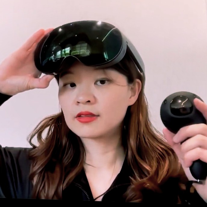 Dominique Wu lifting a VR headset from her eyes, motion controller in hand.